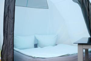 a bed with a canopy with white sheets and pillows at Luxuswohnzelt ZELT UND SAND direkt am Strand in Dranske