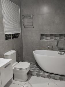 a bathroom with a white tub and a toilet at Inspire living home in Benoni