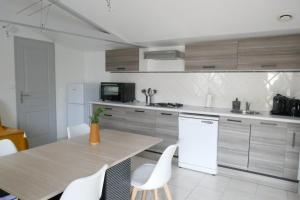 a kitchen with a wooden table and white appliances at Le romarin in Courçon