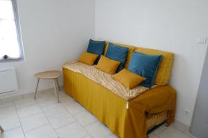 Un sofá amarillo con almohadas azules y amarillas. en Le romarin, en Courçon