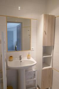 Baño blanco con lavabo y espejo en Le romarin, en Courçon
