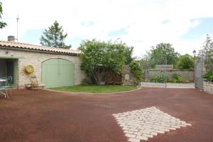 una casa con una entrada con un garaje verde en Le romarin, en Courçon