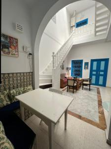 a living room with a white table and stairs at La maison 4 puits in Sidi Bou Saïd