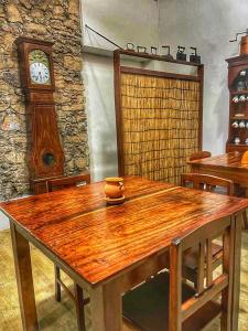 une table en bois dans une chambre avec une horloge dans l'établissement Pousada Praia Maria, à Praia