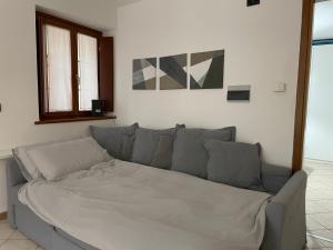 un divano grigio in un soggiorno con due finestre di Oasi Verde con Area Barbecue a Udine