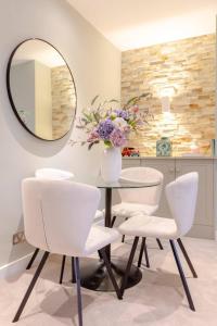 een eetkamer met een glazen tafel en witte stoelen bij Elegant 1BD Flat in the Heart of Notting Hill! in Londen
