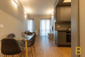 BePlace Apartments in Primaticcio في ميلانو: مطبخ وغرفة طعام مع طاولة وكراسي