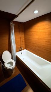 a bathroom with a toilet sitting next to a bath tub at Highfive Hotel Pattaya in Pattaya