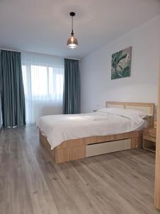 een slaapkamer met een groot bed en een houten vloer bij London Residence - Suceava City - in Suceava