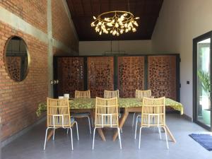 une salle à manger avec une table, des chaises et un lustre dans l'établissement Graha Ayoe, à Sidemen