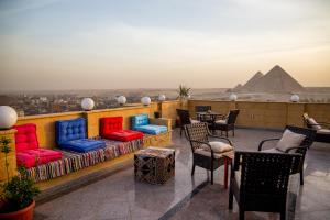 einen Balkon mit Stühlen und Sofas sowie Blick auf die Pyramiden in der Unterkunft Gardenia Apartment Pyramids View in Kairo