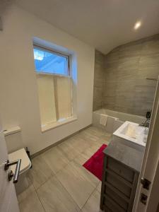 bagno con lavandino, vasca e finestra di Lovely 4-Bed House in Central Wolverhampton a Wolverhampton