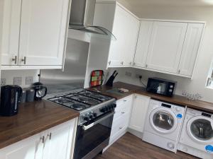 een keuken met een fornuis, een wasmachine en een droger bij Lovely 4-Bed House in Central Wolverhampton in Wolverhampton
