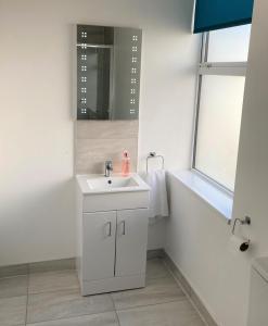 Baño blanco con lavabo y espejo en Lovely 4-Bed House in Central Wolverhampton en Wolverhampton