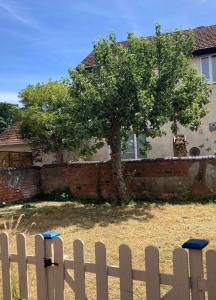 a white fence with a tree in front of a house at Lovely 4-Bed House in Central Wolverhampton in Wolverhampton