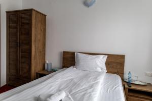 a bed with white sheets and a wooden headboard at Vila Edelweiss in Predeal