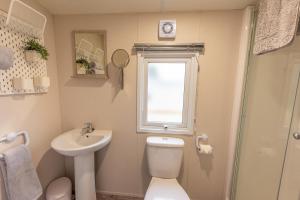 a bathroom with a toilet and a sink and a window at Luxury Chalet Near Dornoch, high speed free Wi-Fi in Dornoch