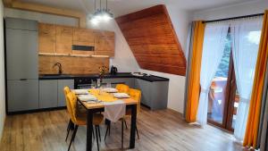 eine Küche mit einem Tisch und gelben Stühlen in einem Zimmer in der Unterkunft Willa Adamówka in Zakopane