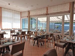 un restaurante con mesas, sillas y ventanas grandes en Art Hotel Aachen, en Aachen