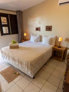 sypialnia z dużym łóżkiem z białą pościelą i poduszkami w obiekcie Pousada Vila Canoa w mieście Canoa Quebrada