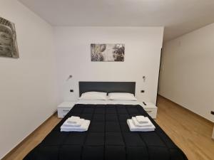 sypialnia z czarnym łóżkiem i 2 ręcznikami w obiekcie Monti Guest House Alghero w mieście Alghero