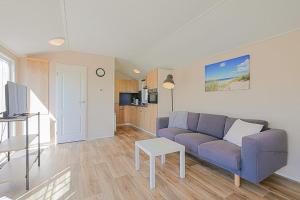 een woonkamer met een paarse bank en een tafel bij Chalet Luttikduin 21, aan het strand met ruime tuin! - Callantsoog in Callantsoog