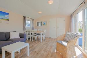 een woonkamer met een bank en een tafel bij Chalet Luttikduin 21, aan het strand met ruime tuin! - Callantsoog in Callantsoog