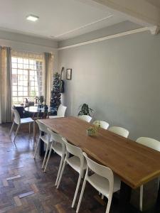 a dining room with a large wooden table and white chairs at Gup Hostel in Curitiba