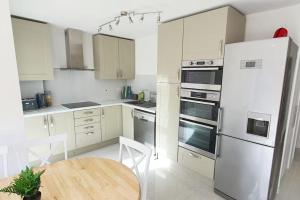 een keuken met witte apparatuur en een houten tafel bij Walnut Flats-F2, 3-Bedroom with Garden & Patio - AC, Parking, Netflix, WIFI - Close to Oxford, Bicester & Blenheim Palace in Oxford