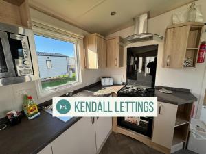 a kitchen with a stove top oven next to a window at Abi in Selsey
