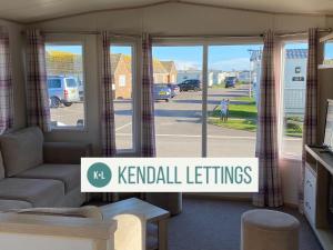 a living room with a couch and some windows at Abi in Selsey +3 photos