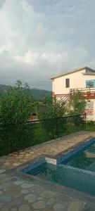 a swimming pool in front of a house at Corbett Bhavesh home Stay in Jhirna