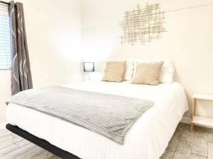 a white bedroom with a bed with white sheets and pillows at Modern Retreat Just Outside The City in San Diego