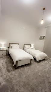 2 letti in una camera con pareti bianche di شقة مميزه a Muhayil