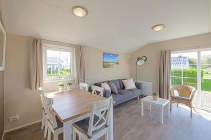 ein Wohnzimmer mit einem Tisch und einem Sofa in der Unterkunft Chalet Luttikduin 22, met ruime tuin! - Callantsoog in Callantsoog