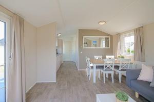 ein Wohnzimmer mit einem Tisch und einem blauen Sofa in der Unterkunft Chalet Luttikduin 22, met ruime tuin! - Callantsoog in Callantsoog