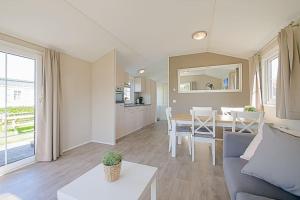 een woonkamer met een bank en een eetkamer bij Chalet Luttikduin 22, met ruime tuin! - Callantsoog in Callantsoog