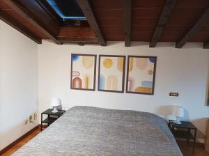 a bedroom with a bed and three paintings on the wall at Villa Camelia Tuscany in Pescia