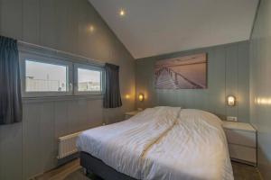 a bedroom with a large bed and two windows at NEW! Strandhuis 't Koepeltje aan zee! in Callantsoog