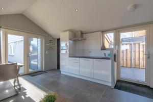 a kitchen with white cabinets and a large window at NEW! Strandhuis 't Koepeltje aan zee! in Callantsoog