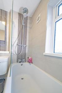 a bathroom with a tub and a shower with a window at Deluxe 2 Bed Apartment- Near Heathrow, Legoland, Windsor Slough in Slough