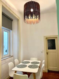 una sala da pranzo con tavolo, sedie e lampadario pendente di Fashion Chiado - SSs Apartments a Lisbona