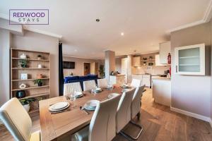 a dining room and kitchen with a wooden table and chairs at Spacious 2 Bed 2 Bath Apartment, Near Train Station, FREE Parking By REDWOOD STAYS in Woking