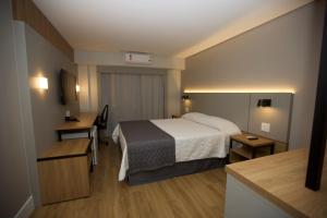 a hotel room with a bed and a desk at Mogano Business Hotel- ELETROPOSTO in Chapecó