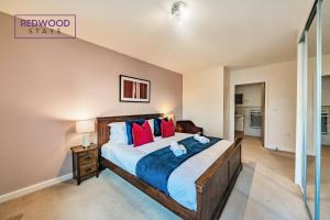 a bedroom with a large bed with red pillows at Spacious 2 Bed 2 Bath Apartment, Near Train Station, FREE Parking By REDWOOD STAYS in Woking