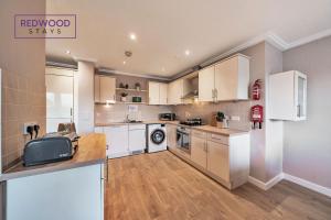 a large kitchen with white cabinets and a sink at Spacious 2 Bed 2 Bath Apartment, Near Train Station, FREE Parking By REDWOOD STAYS in Woking