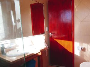 baño con puerta roja y lavamanos en Chiway, en Villa Gesell