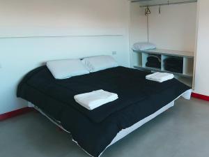 1 dormitorio con 1 cama negra grande y 2 almohadas en Chiway en Villa Gesell