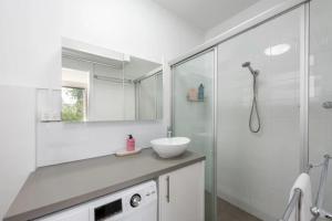 a white bathroom with a sink and a shower at Lovely Studio with Free Parking in East Melbourne! in Melbourne