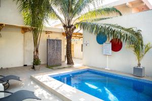 a swimming pool with palm trees in a courtyard at Le Karé Ébène in Cotonou